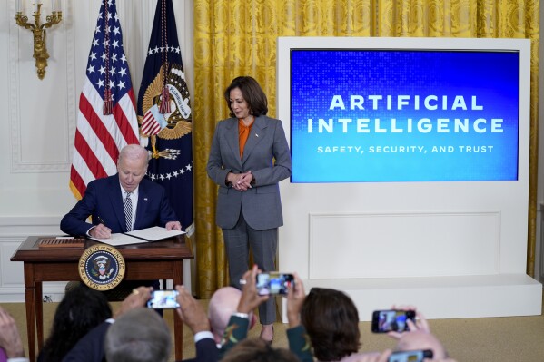 FILE - President Joe Biden signs an executive on artificial intelligence in the East Room of the White House, Oct. 30, 2023, in Washington. Vice President Kamala Harris looks on at right. (AP Photo/Evan Vucci, File)