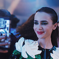 Lily Collins as Emily takes a picture with her phone in Season 4 of 'Emily in Paris.'