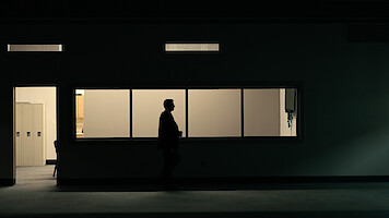 A shadowy figure stands in a dimly lit room.