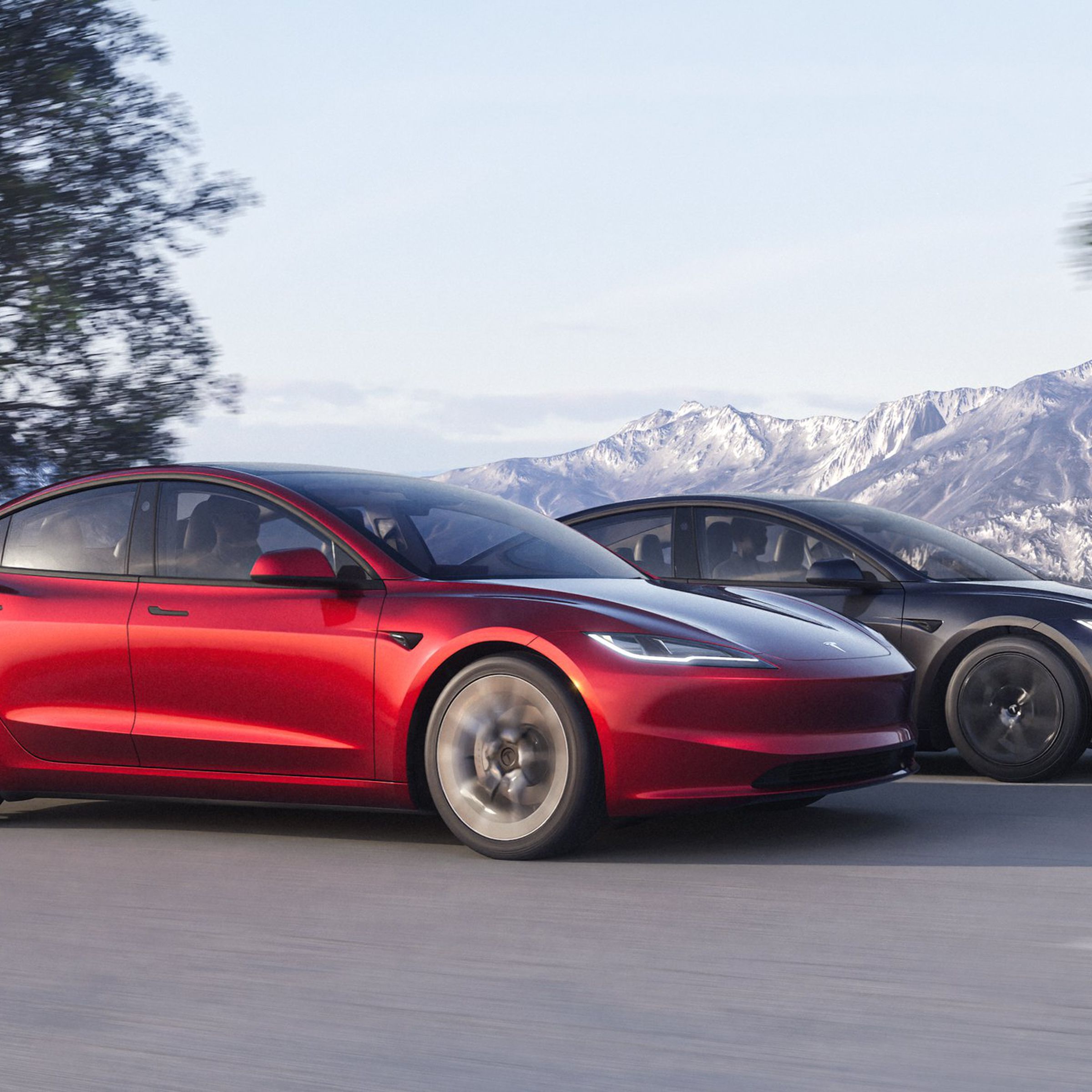 Two Tesla Model 3s shown driving on a mountain road, one red and one gray.