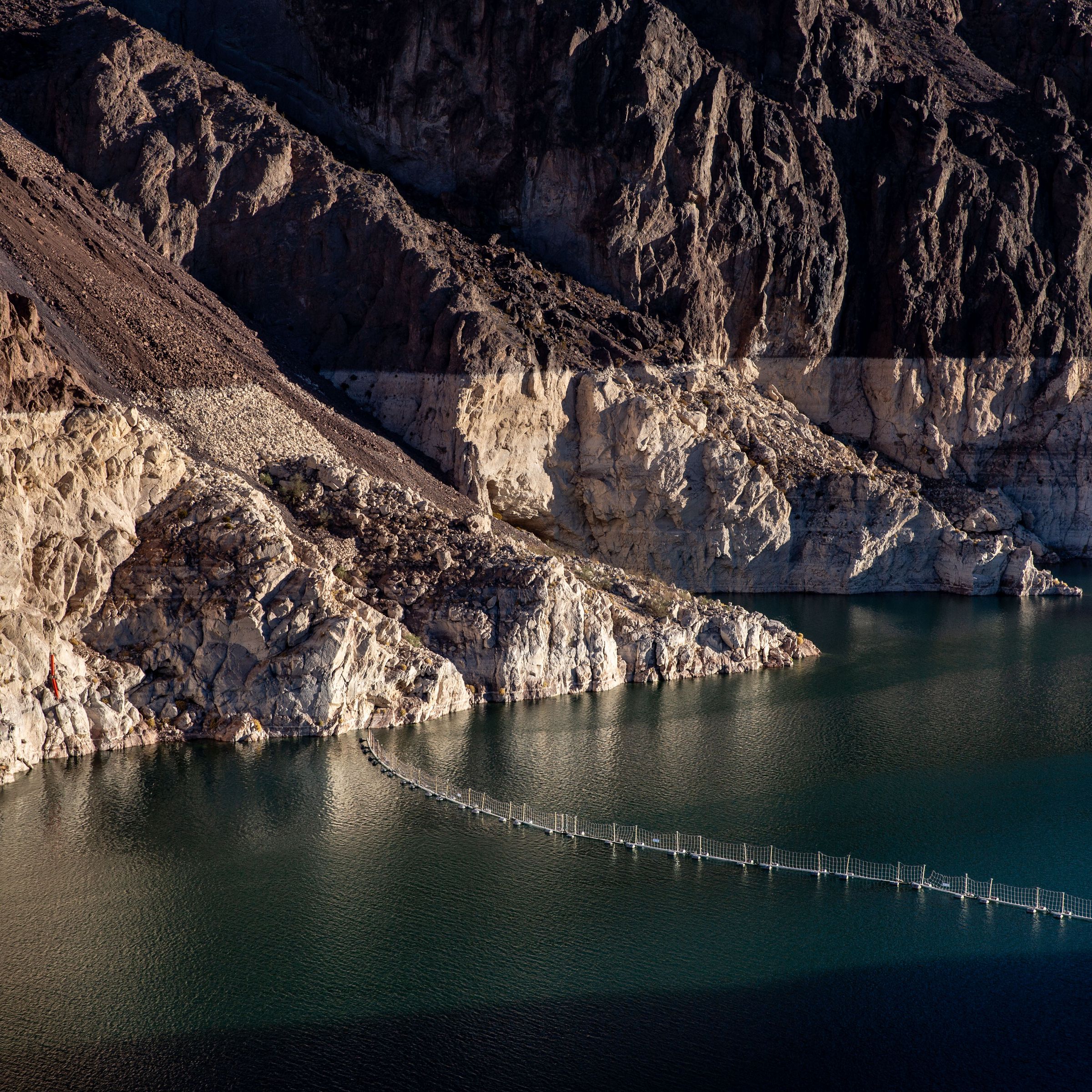 A half-empty water reservoir, with a pale layer of rocks above the waterline showing how high the water used to be.