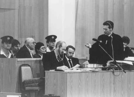 Chief defense attorney Mark O'Conner (standing) addresses a question to John Demjanjuk during Demjanjuk's trial. [LCID: 65259]