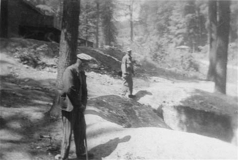 Two survivors at one of the human-ash pits in the Dora-Mittelbau concentration camp, located near Nordhausen. [LCID: 01280]