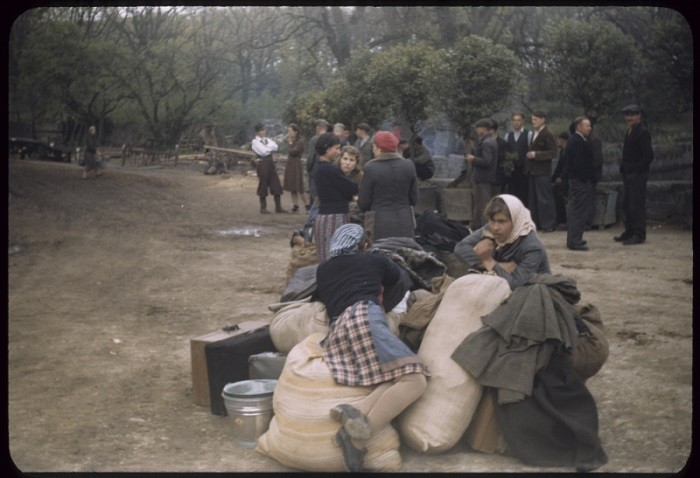 Displaced persons wait next to their suitcases and bundles, place uncertain, ca.