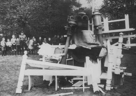 German children, behind an SS man, watch as religious objects from the Zeven synagogue are set on fire during Kristallnacht (the ... [LCID: 4318]