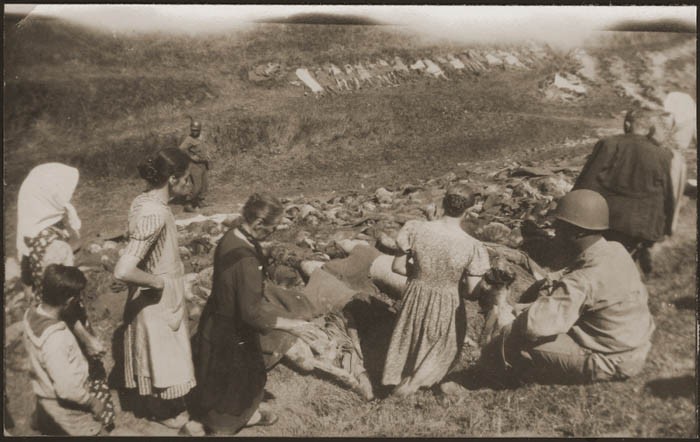 African American soldiers escort German civilians through a site where camp prisoners were massacred during a death march from Buchenwald. [LCID: 85740]