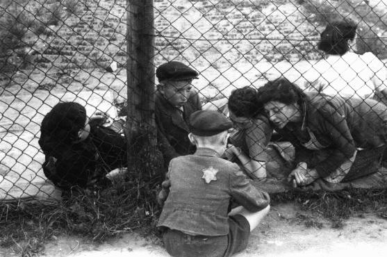 Family members say goodbye to a child through a fence at the ghetto's central prison where children, the sick, and the elderly were ...