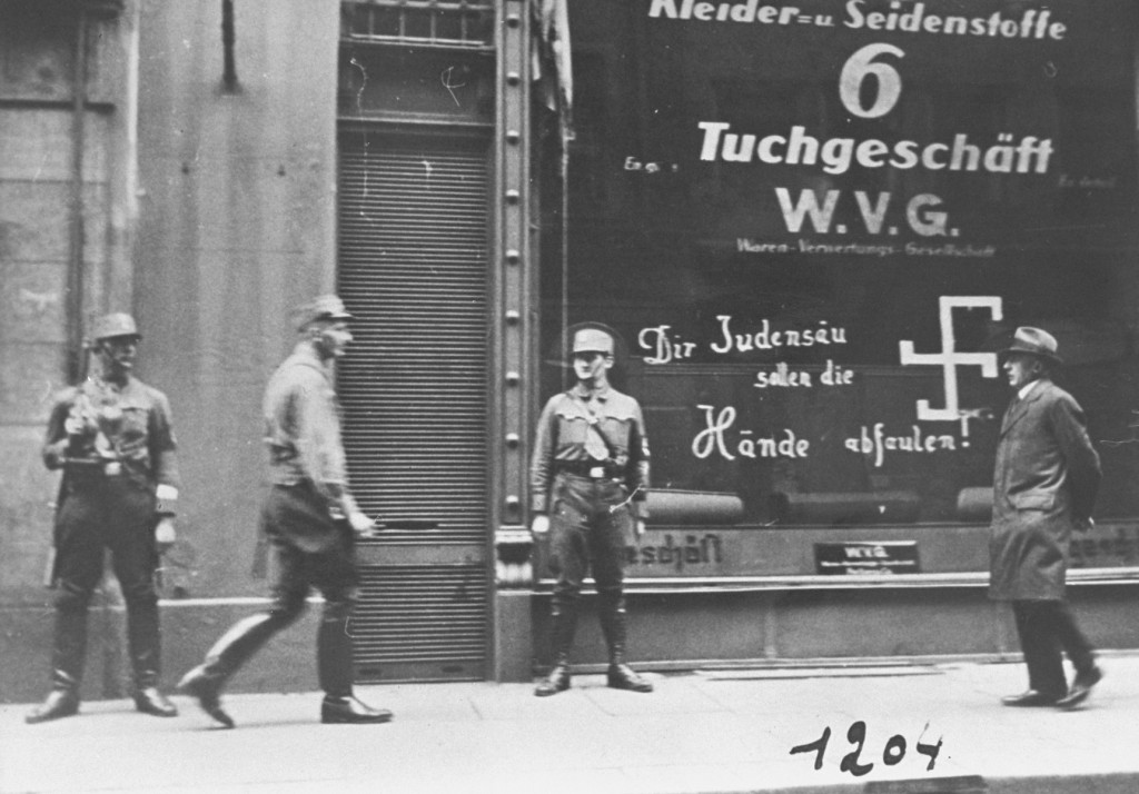 Shortly after the German annexation of Austria, Nazi Storm Troopers stand guard outside a Jewish-owned business. [LCID: 29034]