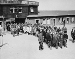 Escoltados por soldados estadounidenses, niños sobrevivientes de Buchenwald salen por la puerta principal del campo. Buchenwald, Alemania, 27 de abril de 1945.