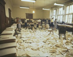 Imagem da sala do mimeógrafo no Palácio da Justiça em Nuremberg, 1948. A reprodução de documentos durante os julgamentos de Nuremberg, muitas vezes em quatro línguas, foi um enorme desafio logístico.