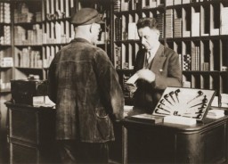 Arthur Lewy with a customer in his tobacco shop in Berlin. Arthur was arrested in 1938 and was forced to sell his business after his release. Berlin, Germany, 1938.