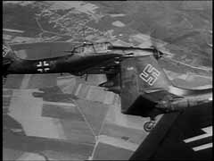 Les Junkers (Ju) 87, connu sous le nom de "stukas" furent l'un des éléments décisifs du succès du Blitzkrieg ("guerre étoile") lors de l'offensive à l'ouest de 1940. Ils appuyèrent de près les troupes allemandes opérant au sol, détruisant avions, terrains d'atterrissage et autres objectifs ennemis et semant la panique dans les arrières. Quoique lents et faciles à abattre par les chasseurs alliés, les stukas se révélèrent terriblement efficaces lors de l'invasion de la Pologne et de l'Europe occidentale, où les Allemands bénéficiaient de la suprématie aérienne. Ils provoquaient la terreur parmi les forces alliées opérant au sol, qui apprirent à reconnaître le sifflement caractéristique de leurs piqués. Ces images d'actualités allemandes montrent (depuis le ciel et depuis le sol) les destructions causées par les attaques des stukas pendant la campagne occidentale dans les Flandres.