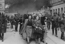 Soldados alemães levam judeus capturados durante a revolta no gueto de Varsóvia para o ponto de agrupamento dos prisioneiros a serem deportados para os campos de extermínio.  Polônia, maio de 1943.