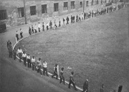 Para tahanan melakukan mars di halaman markas Gestapo di Nuremberg. Keterangan ilustrasi asli foto berbunyi: "Halaman markas Gestapo, Nurnberg. Yang terdapat di foto tampaknya para laki-laki Prancis yang dibawa ke Jerman sebagai pekerja budak".
 