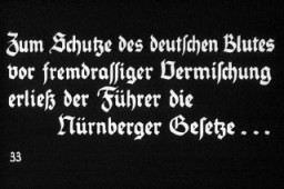 “Almanya, Yahudi Halkının Üstesinden Gelir” başlıklı Hitler Gençliği eğitim sunusunun 33. Nazi propaganda slaydı. Almanca metin şöyle: “Zum Schutze des deutschen Blutes vor fremdrassiger Vermischung erliess der Fuhrer die.” Çeviri: “Alman kanını yabancı ırkla karışmaya karşı korumak için Führer Nuremberg Yasaları’nı çıkardı.”