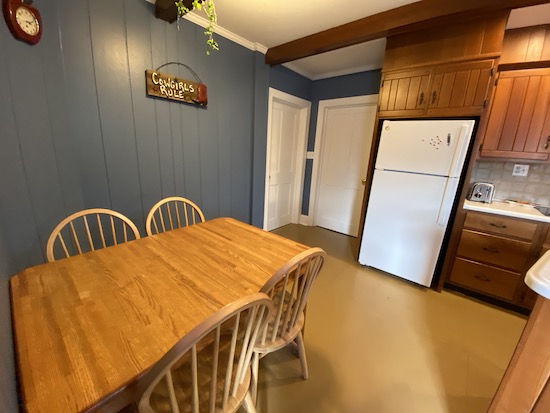 Two closed white doors in a kitchen with a wooden table and a sign on the wall that says Cowgirls Rule