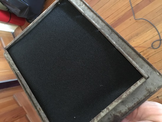 A rectangular air grate with a black filter inserted into it.