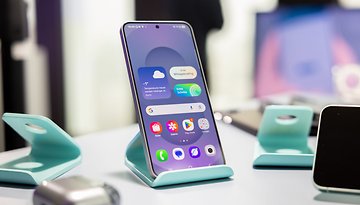 Samsung Galaxy S25 displayed on a teal stand with a colorful app interface.