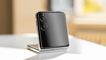 A Xiaomi Mix Flip smartphone standing on a table, showcasing its sleek design and dual camera setup.