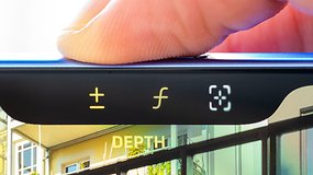 Close-up of an iPhone 16 screen showing depth adjustment buttons and a user's finger hovering above.