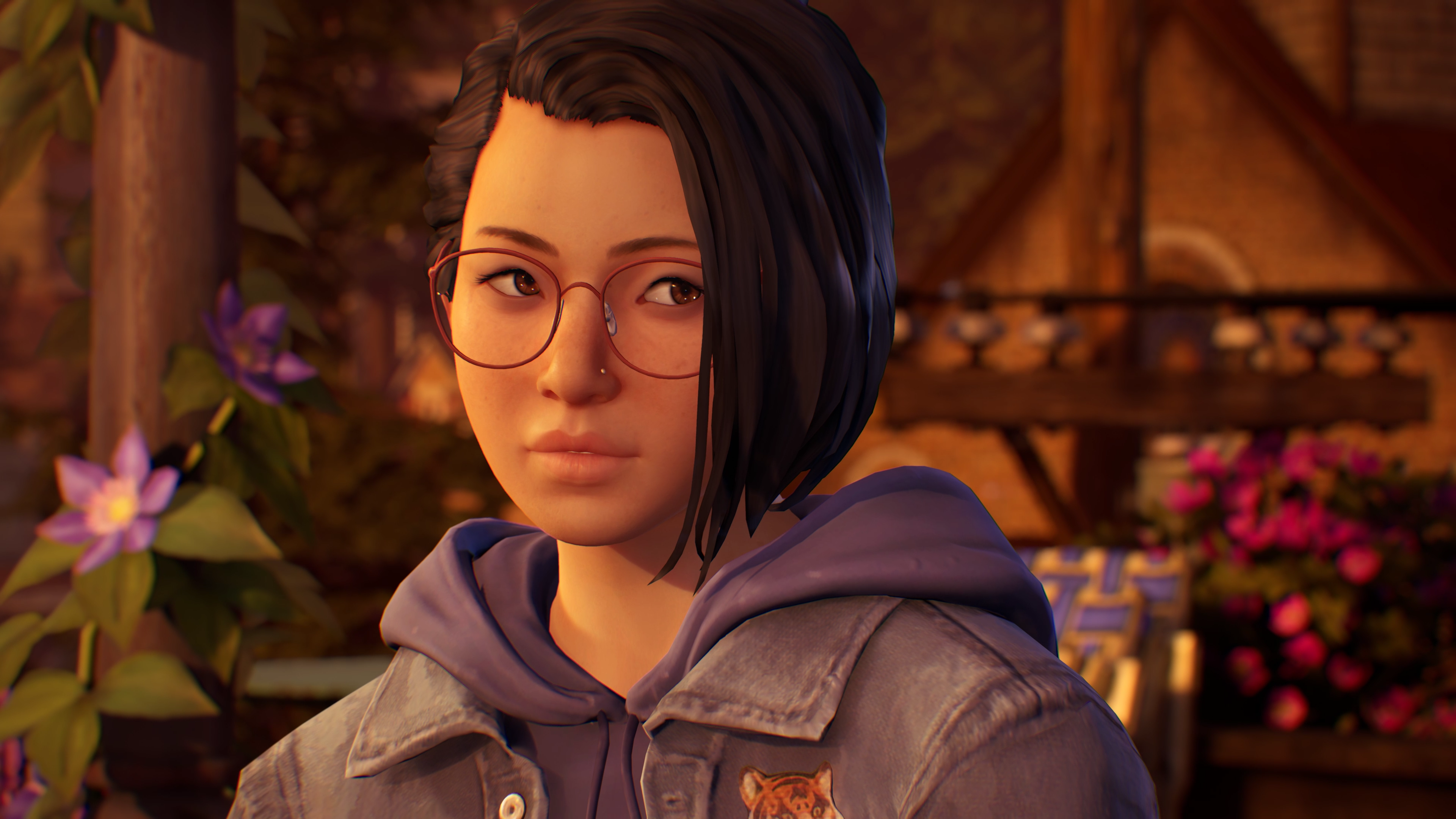 Alex Chen, a young woman in a jean jacket, lit by a mountain sunset. She shoots a guarded look through round red glasses.