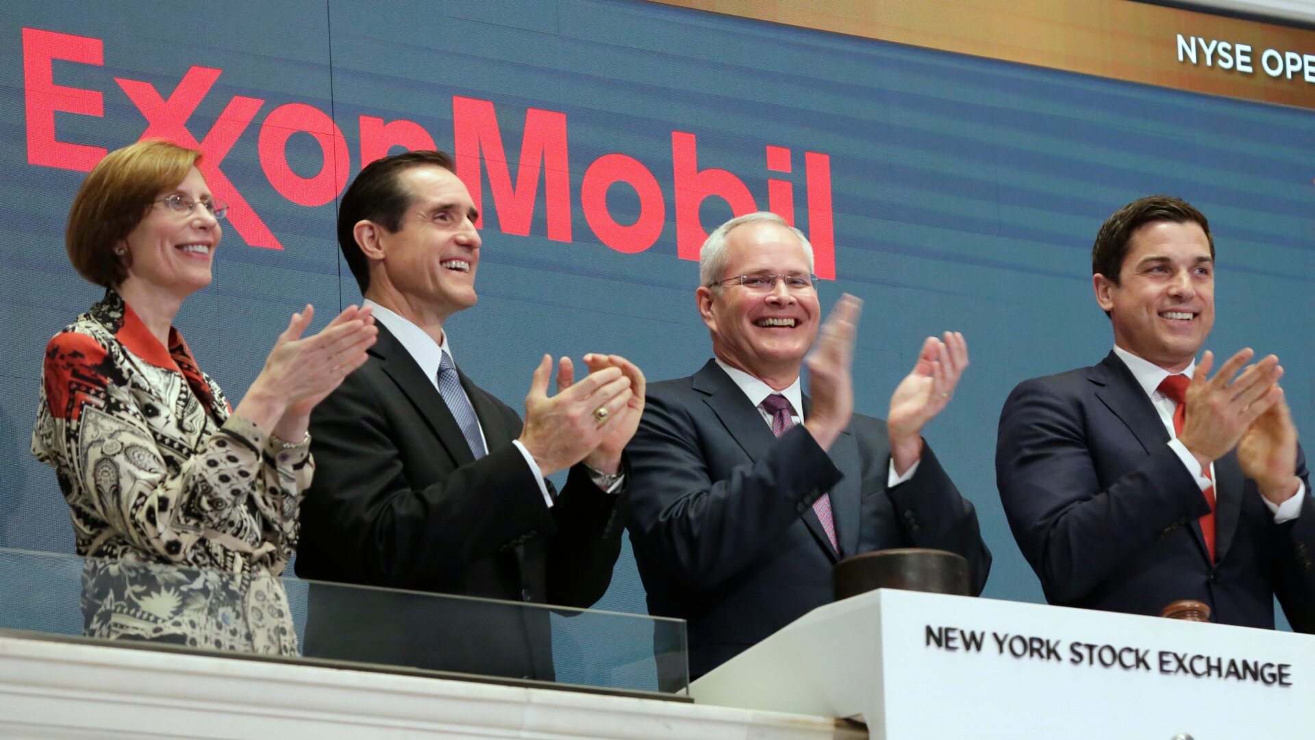 Exxon CEO Darren Woods (second from right) clapping at the New York Stock Exchange because money.