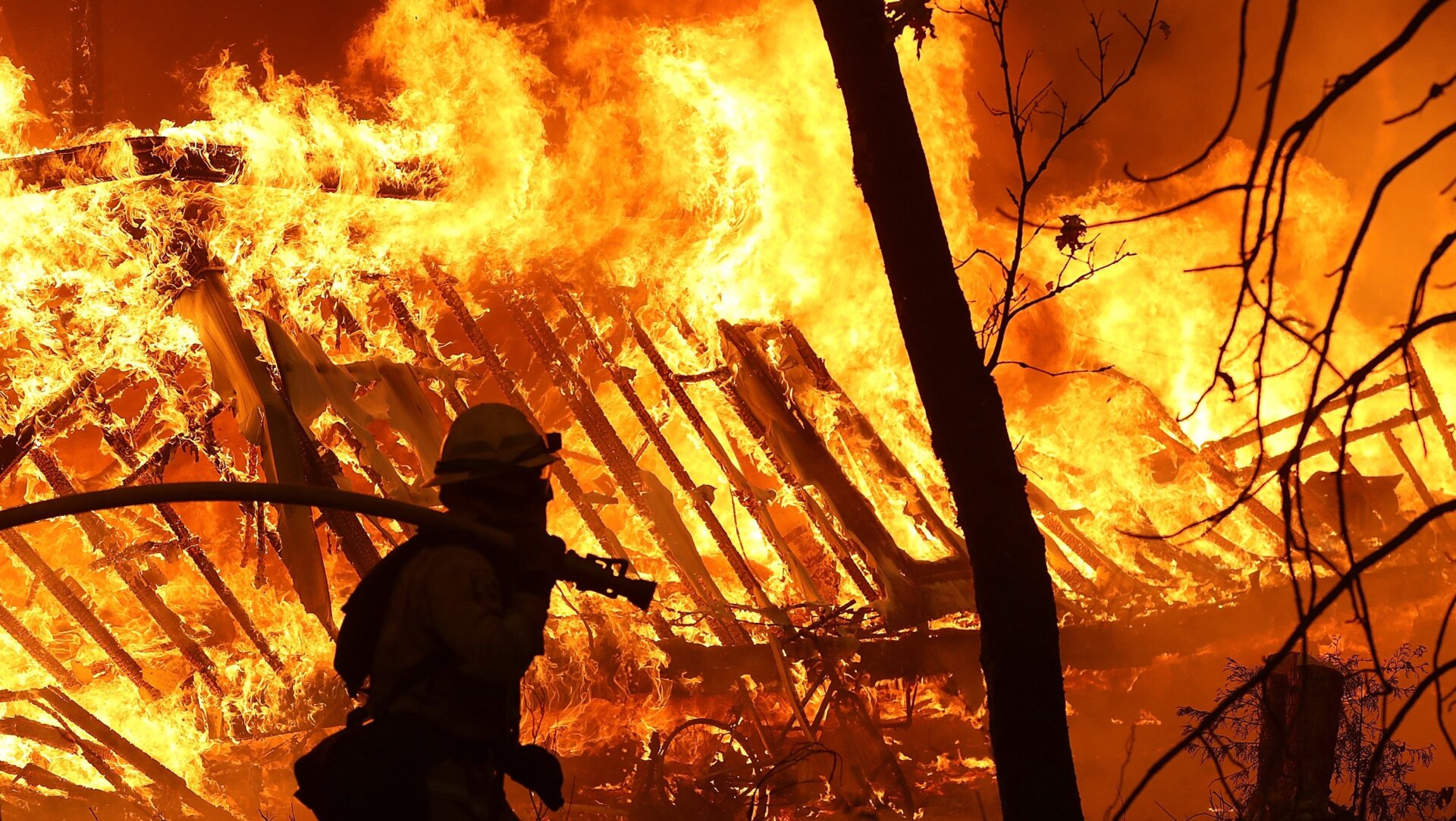 A Cal Fire firefighter monitors a burning home as the Camp Fire moves through Magalia, California on Nov. 9, 2018.