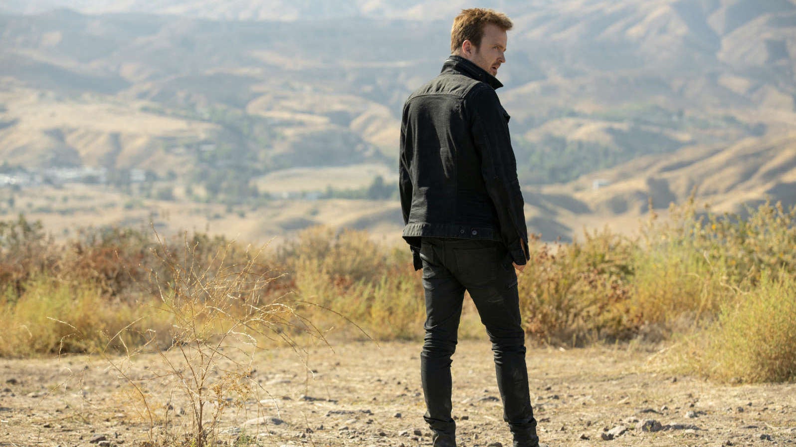 Caleb (Aaron Paul), a man in black.