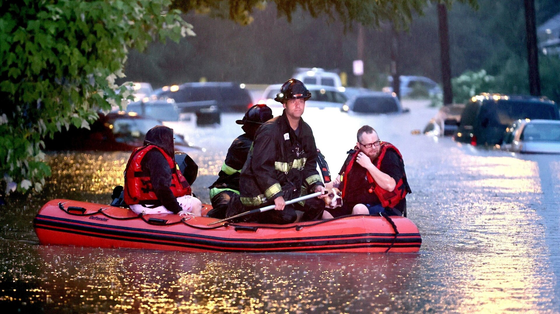 Steven Bertke and his dog Roscoe are taken to dry land by St. Louis firefighters who used a boat to rescue people from their flooded homes on Hermitage Avenue in St. Louis on Tuesday, July 26, 2022.