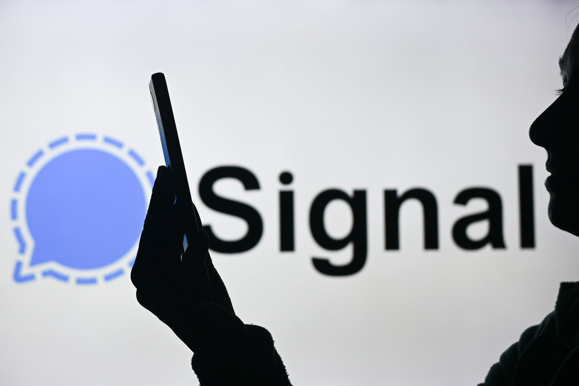 An image of a woman holding a cell phone in front of the Signal logo displayed on a computer screen, on April 29, 2024, in Edmonton, Canada.