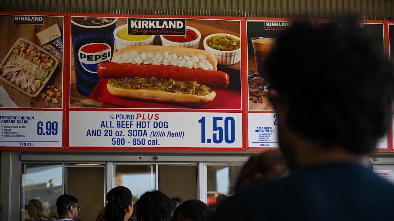 Customers wait in line to order below signage for the Costco Kirkland Signature $1.50 hot dog and soda combo, which has maintained the same price since 1985 despite consumer price increases and inflation, at the food court outside a Costco Wholesale Corp. warehouse store in Inglewood, California, on June 12, 2024.