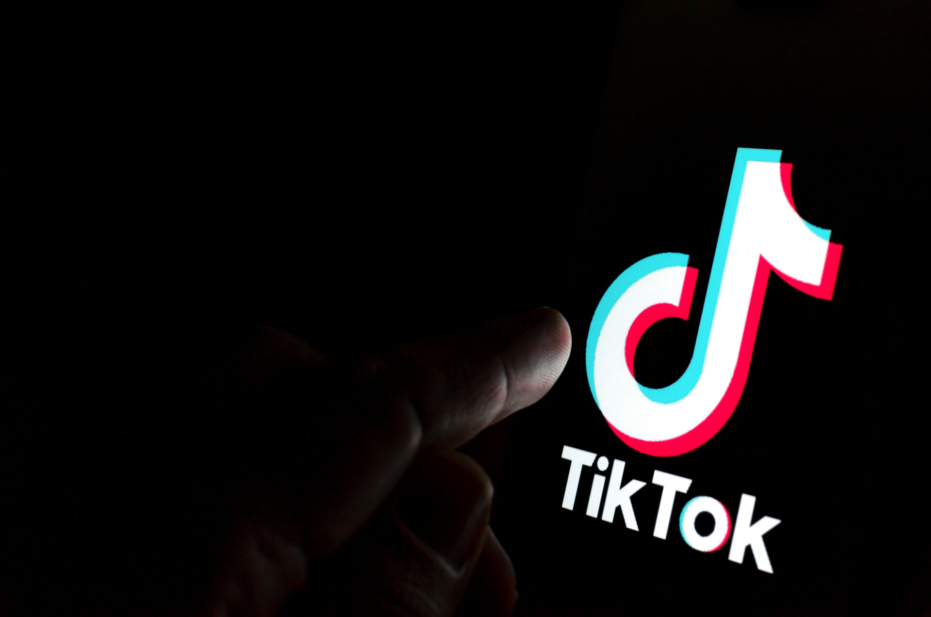 A finger pointing at the tiktok logo on a screen