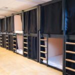 Picture of a row of double-stacked bunkbed "pods" with privacy curtains.