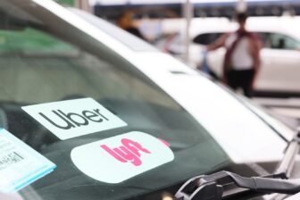 Uber and Lyft stickers displayed on the windshield of a car.