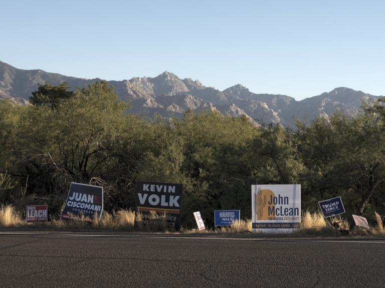 political signs line a highway near a high, dry mountain range