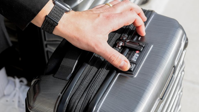 person locking Samsonite suitcase