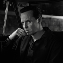 A man sits in a dark taxi looking intense.