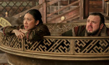 Two people in ancient Chinese robes sit in a golden cauldron looking worried.