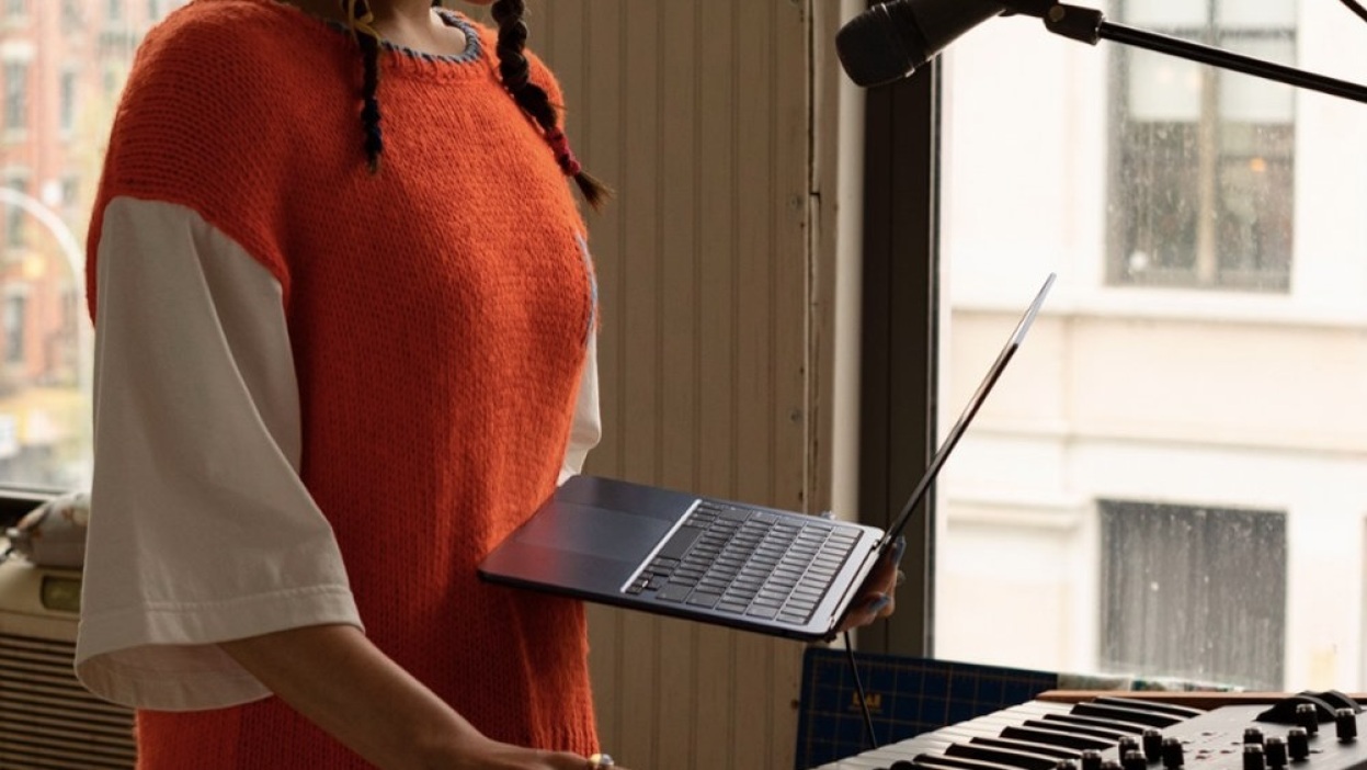 person holding m2 macbook air in front of piano