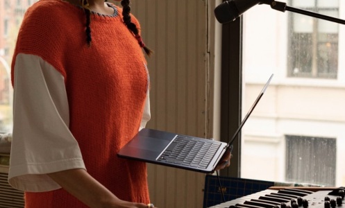 person holding m2 macbook air in front of piano