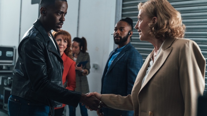 The Doctor shakes hands worriedly with a familiar woman in a business suit. 