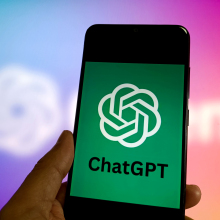 A hand holds a phone with the ChatGPT logo on the screen.