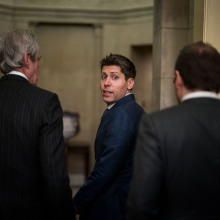 Sam Altman looks behind him with a startled expression, walking through the U.S. Capitol building.