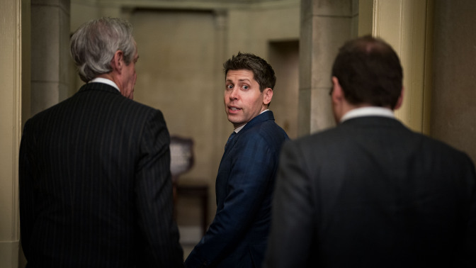 Sam Altman looks behind him with a startled expression, walking through the U.S. Capitol building.