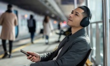 person sitting at train station wearing sony wh-1000xm5 