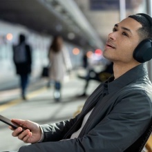 person sitting at train station wearing sony wh-1000xm5 