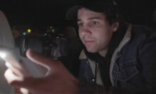 David Dobrik looking at a phone, holding his camera in the other hand.