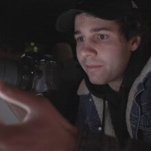 David Dobrik looking at a phone, holding his camera in the other hand.