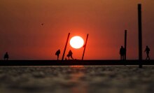 A bright orange sun sits in the horizon above Lake Michigan on a hot day in Chicago.