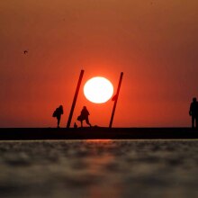 A bright orange sun sits in the horizon above Lake Michigan on a hot day in Chicago.